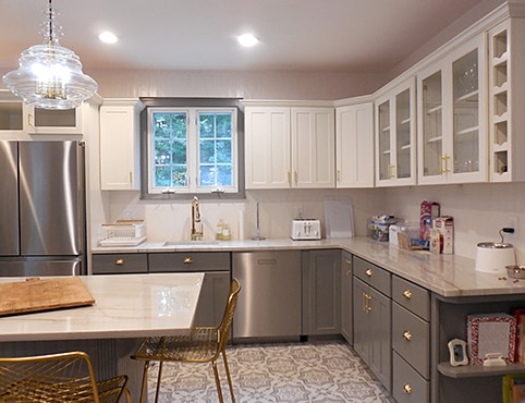 After photo of a large repainted two-toned kitchen featuring white upper cabinets and gray lower cabinets with a matching gray island. After photo of a large repainted two-toned kitchen featuring white upper cabinets and gray lower cabinets with a matching gray island.