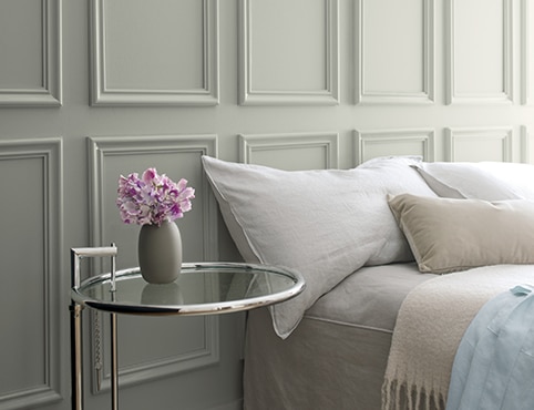 A gray bedroom wall with a glass bedside table. A gray bedroom wall with a glass bedside table.