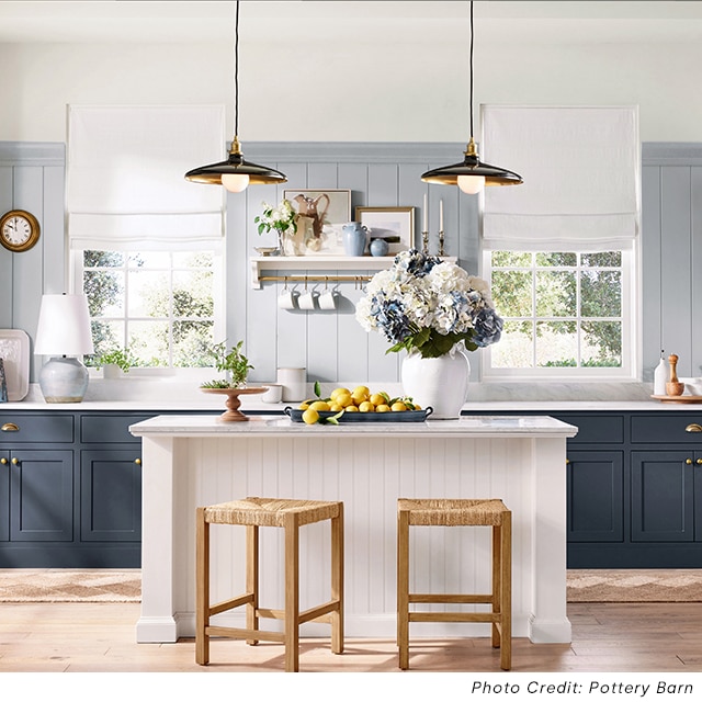 A kitchen with blue painted shiplap walls on the lower section of the walls, off-white painted upper, blue painted cabinets, a white painted island, and various decorations on marble countertops. A kitchen with blue painted shiplap walls on the lower section of the walls, off-white painted upper, blue painted cabinets, a white painted island, and various decorations on marble countertops.