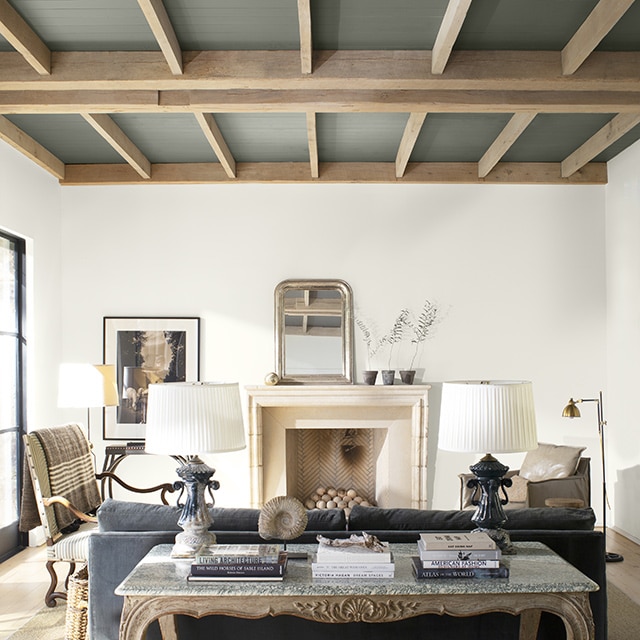 A neutral palette living room with a high, gray painted shiplap ceiling with wood beams. A neutral palette living room with a high, gray painted shiplap ceiling with wood beams.