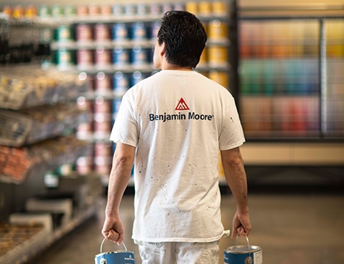 A painting contractor carries cans of premium paint through a Benjamin Moore® independent retailer.  A painting contractor carries cans of premium paint through a Benjamin Moore® independent retailer.