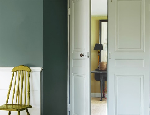 A hallway with white painted doors and a green chair A hallway with white painted doors and a green chair