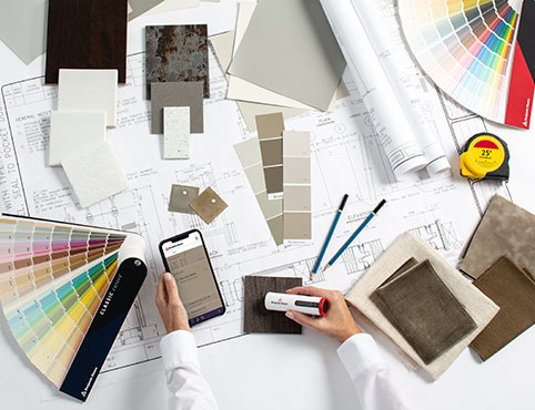 A professional evaluating different paint color swatches and tools to complete their color portfolio. A professional evaluating different paint color swatches and tools to complete their color portfolio.