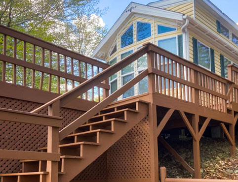 Stairs leading up to the deck of a beige house with large windows. Stairs leading up to the deck of a beige house with large windows.