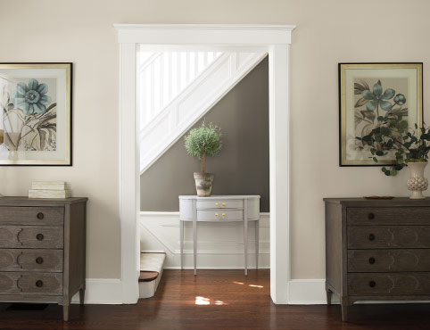 A gray and neutral hallway leads to a white staircase. A gray and neutral hallway leads to a white staircase.