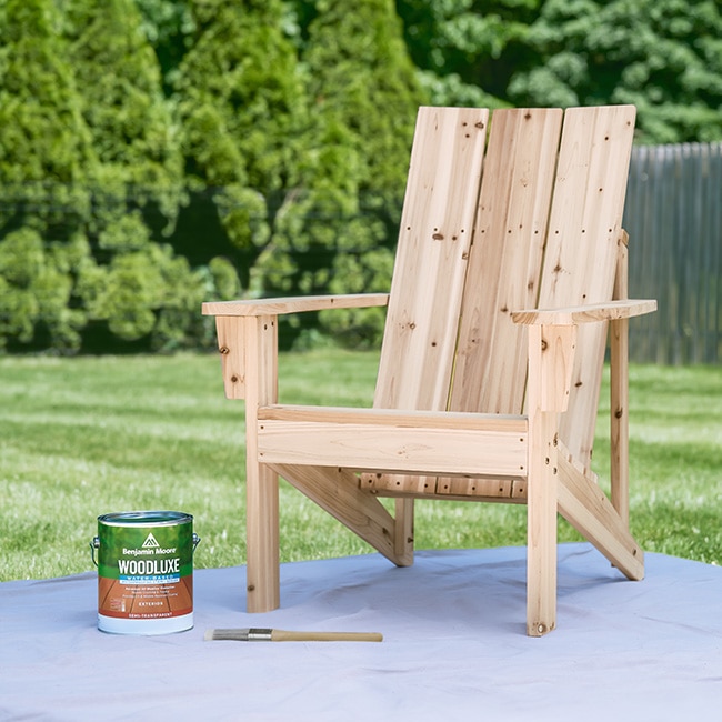 A gallon of Woodluxe® Exterior Stain and a paintbrush next to a wooden Adirondack chair. A gallon of Woodluxe® Exterior Stain and a paintbrush next to a wooden Adirondack chair.