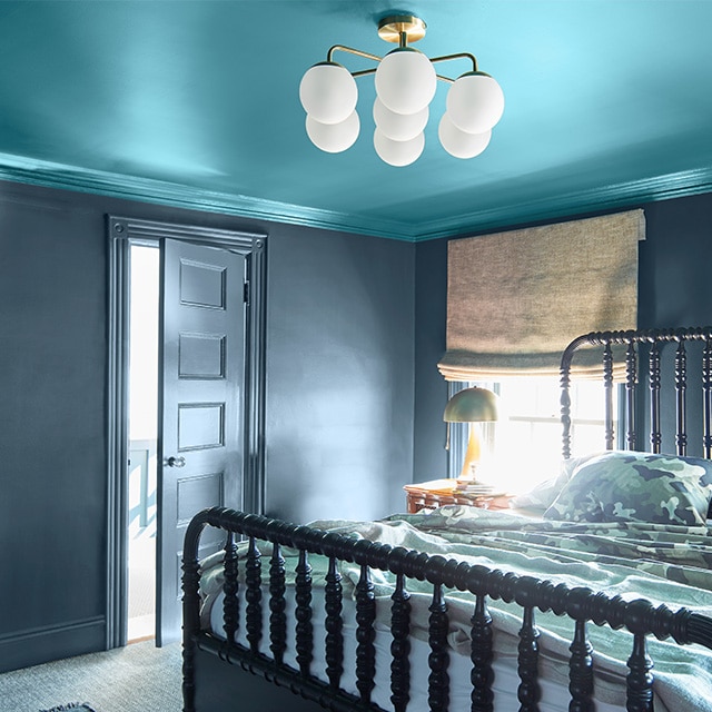 This cozy bedroom features a teal painted ceiling and crown molding; dark gray walls, trim, and door; and a spindle bed. This cozy bedroom features a teal painted ceiling and crown molding; dark gray walls, trim, and door; and a spindle bed.