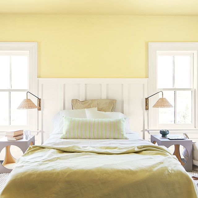 A sunny bedroom with a yellow-painted wall and ceiling, white wainscoting and trim, yellow and white bedding, two reading lamps and side tables. A sunny bedroom with a yellow-painted wall and ceiling, white wainscoting and trim, yellow and white bedding, two reading lamps and side tables.